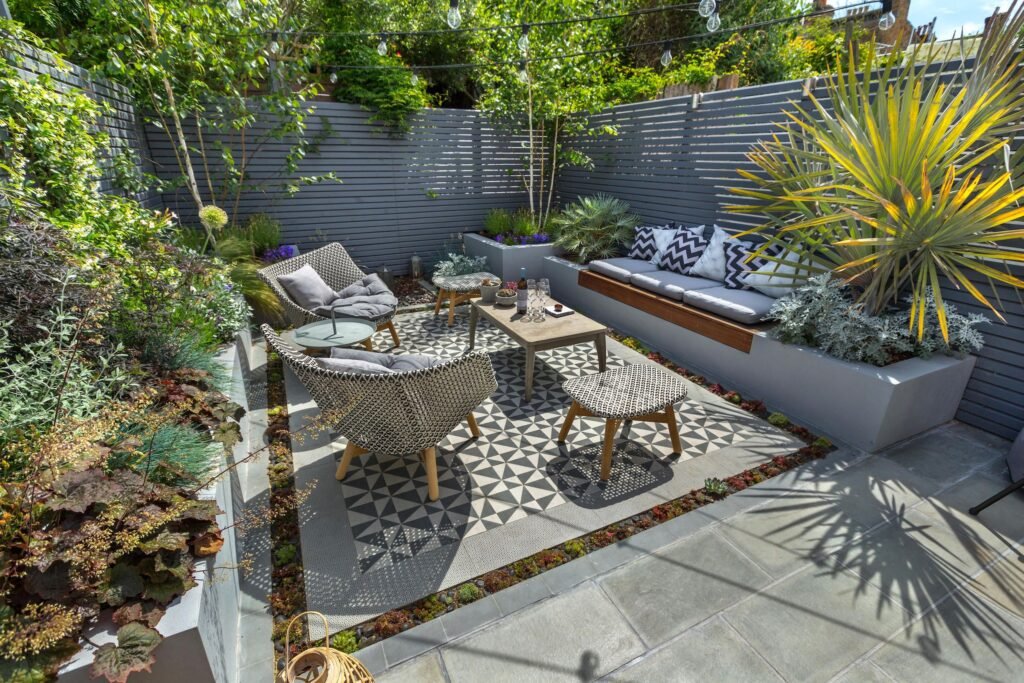 a picture of 2 chairs, 2 stools, a table on a low maintenance garden 